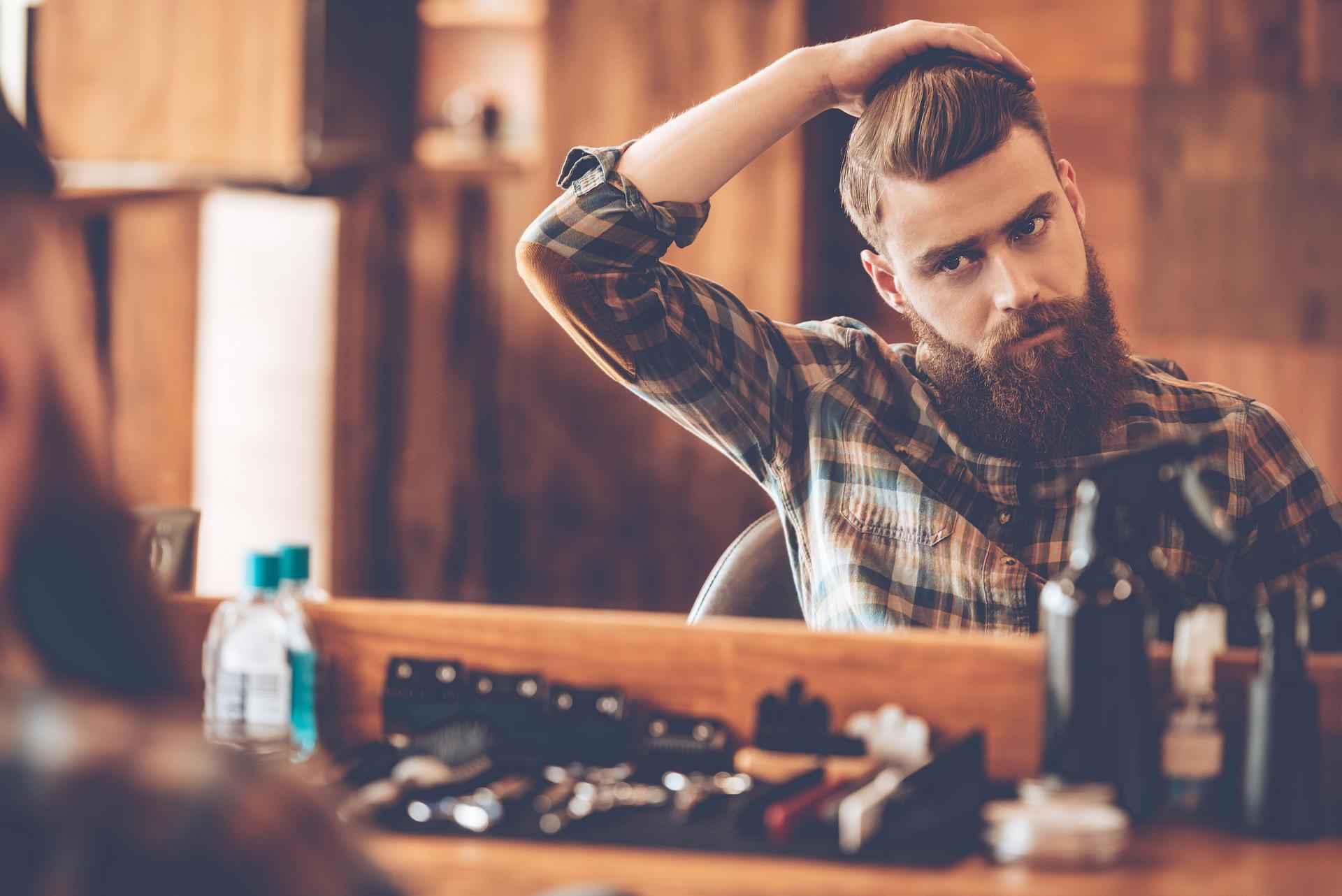 Well-groomed man with a trimmed beard and styled hair using natural grooming products.